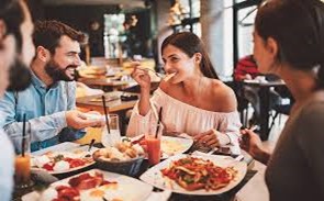 A group of people sitting at a table eating pizzaDescription automatically generated with medium confidence